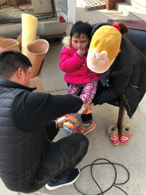 图为市残联康复部工作人员杨威祥为脑瘫儿童安装矫正器